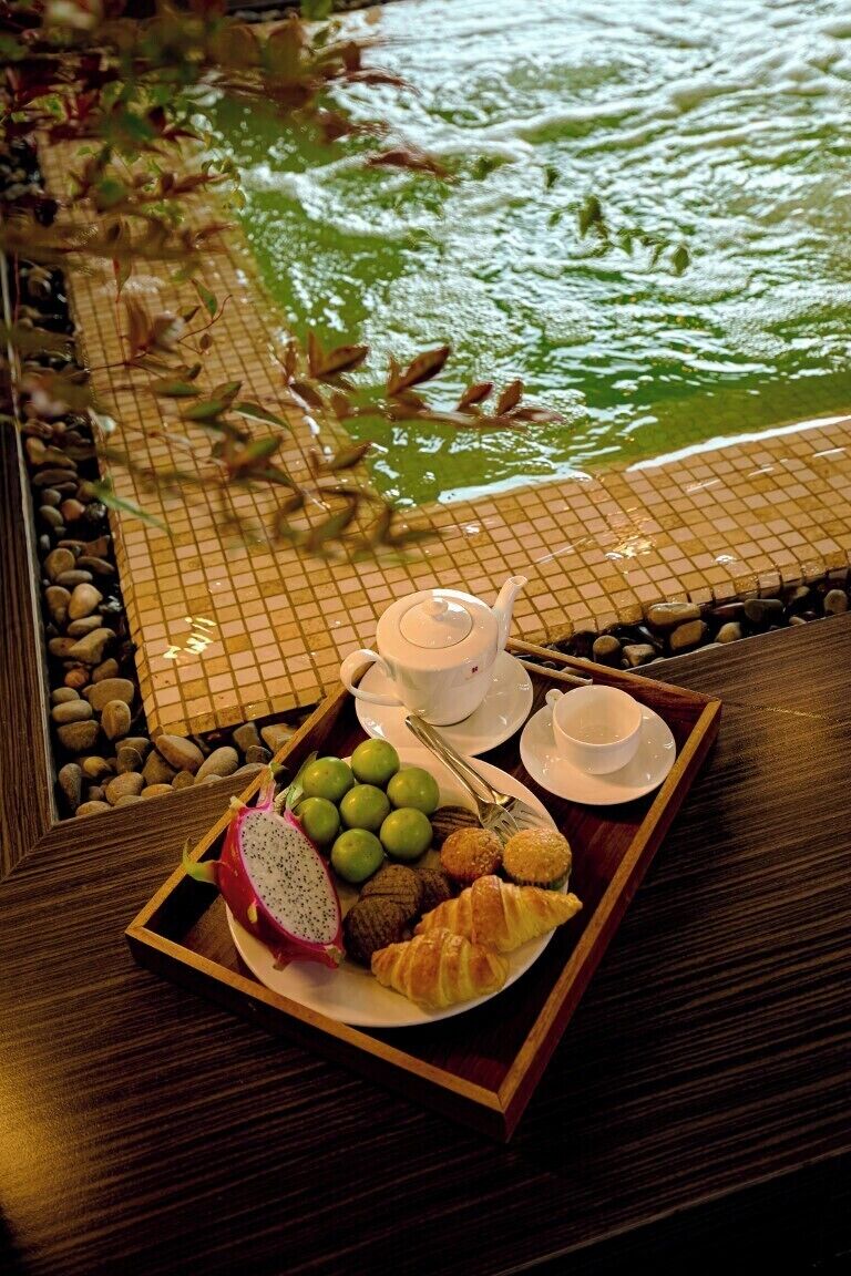 Un vassoio con cibo e un teiera su un tavolo vicino a una fontana.