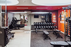 Un gimnasio con cintas de correr, mancuernas y equipo de levantamiento de pesas.