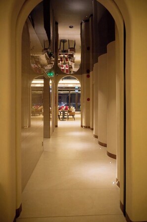 A hotel corridor with arched ceilings, a dining area in the background, and a view of the cityscape through large windows. - The IRIS Signature Hotel & Spa (Can Tho)