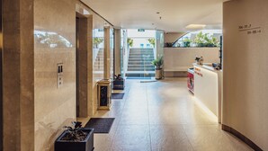 Un vestíbulo de hotel con un mostrador de recepción, una escalera y una planta en maceta.
