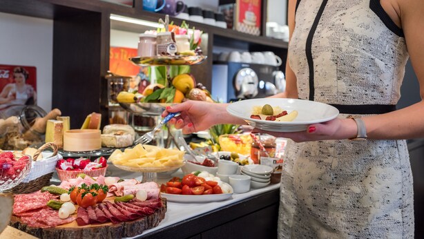 Un bufé con diferentes opciones de comida y una persona serviéndose.