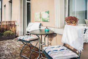 A small outdoor seating area with a round table and two chairs, a potted plant, and artwork on the wall. - Boutique Hotel NI-MO (Zürich)