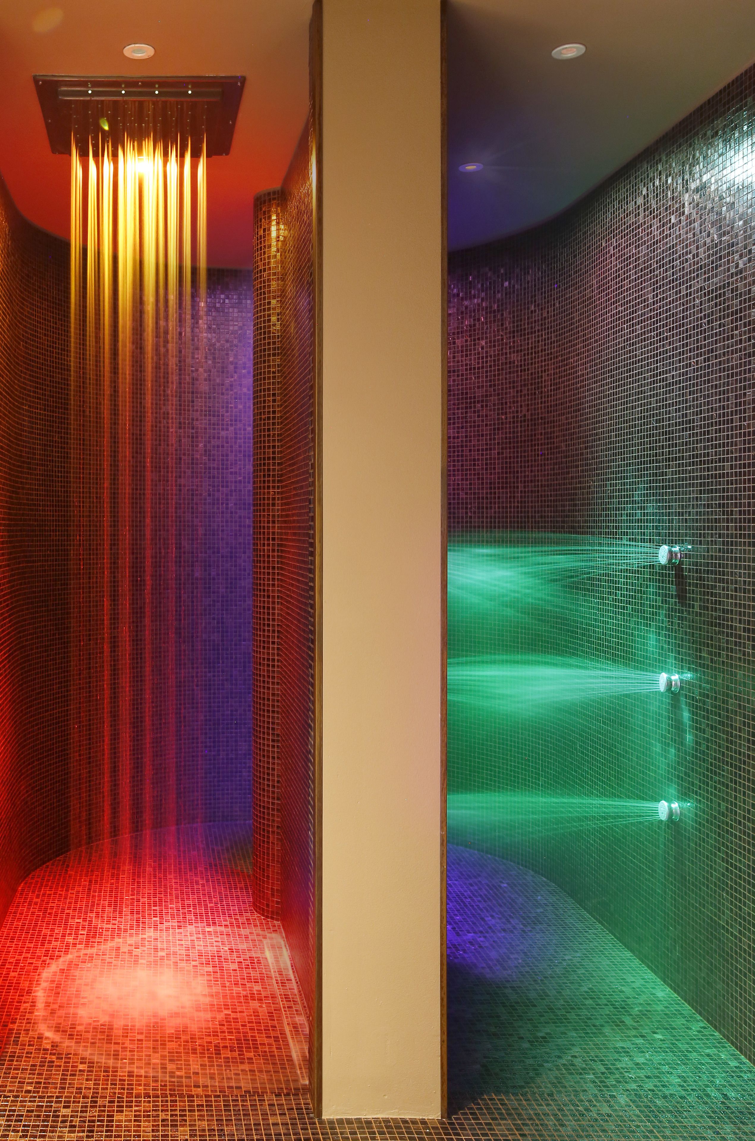 Un bagno moderno con cabina doccia in vetro, pavimento piastrellato e elemento decorativo a tema acqua.