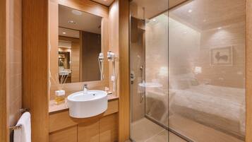 Un baño moderno con un espejo grande, un lavabo y una ducha con mampara de vidrio.