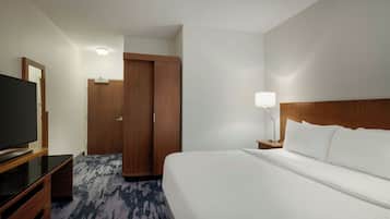 Ett hotellrum med en stor säng, en TV, en garderob och en sänglampa.