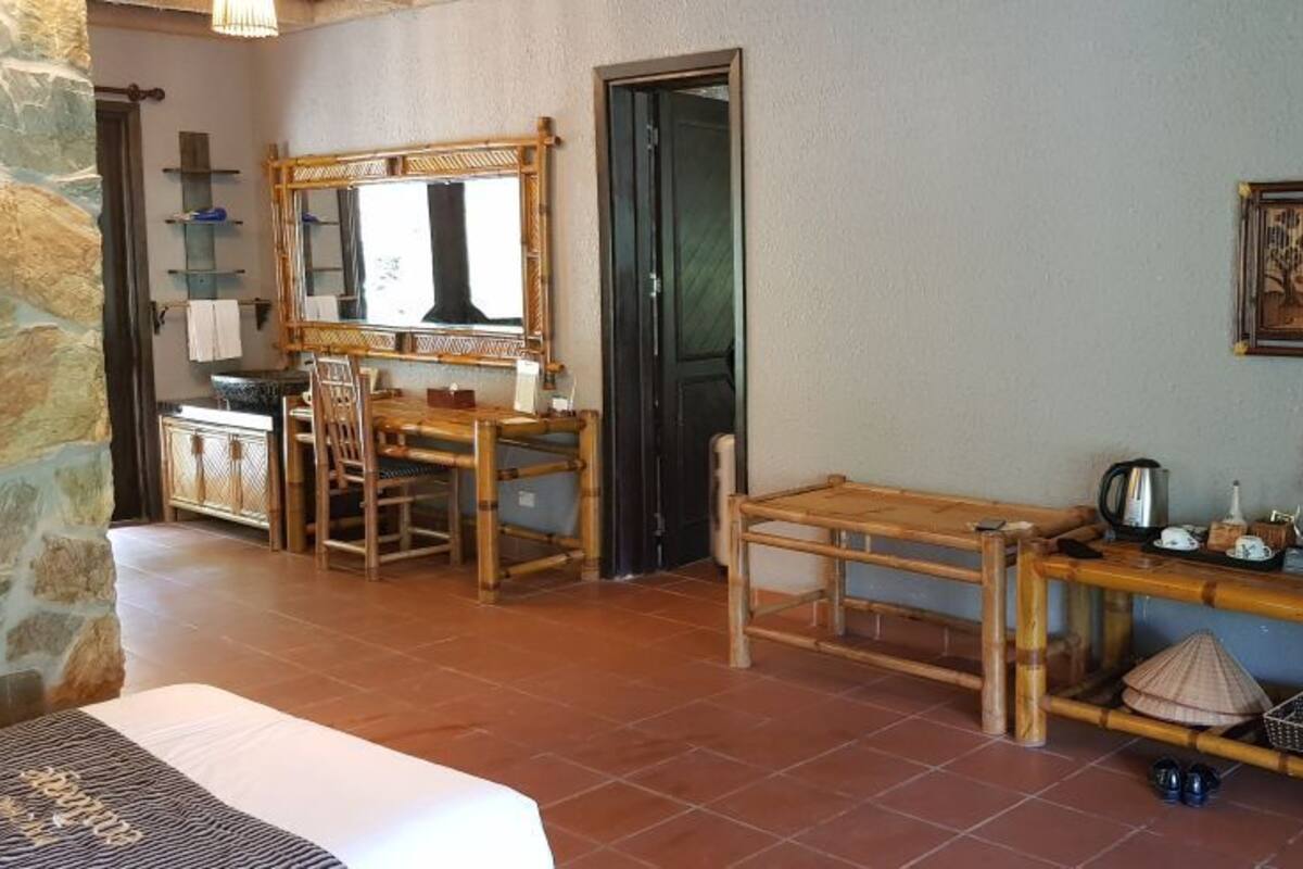 Een kamer met een bed, een houten eettafel, een kitchenette en een grote spiegel.