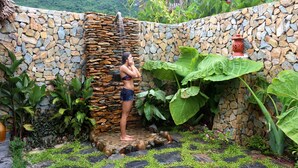 Un muro de piedra con una fuente de agua y abundante vegetación.