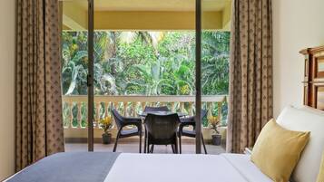 A hotel room with a balcony, a bed, a table, and chairs.