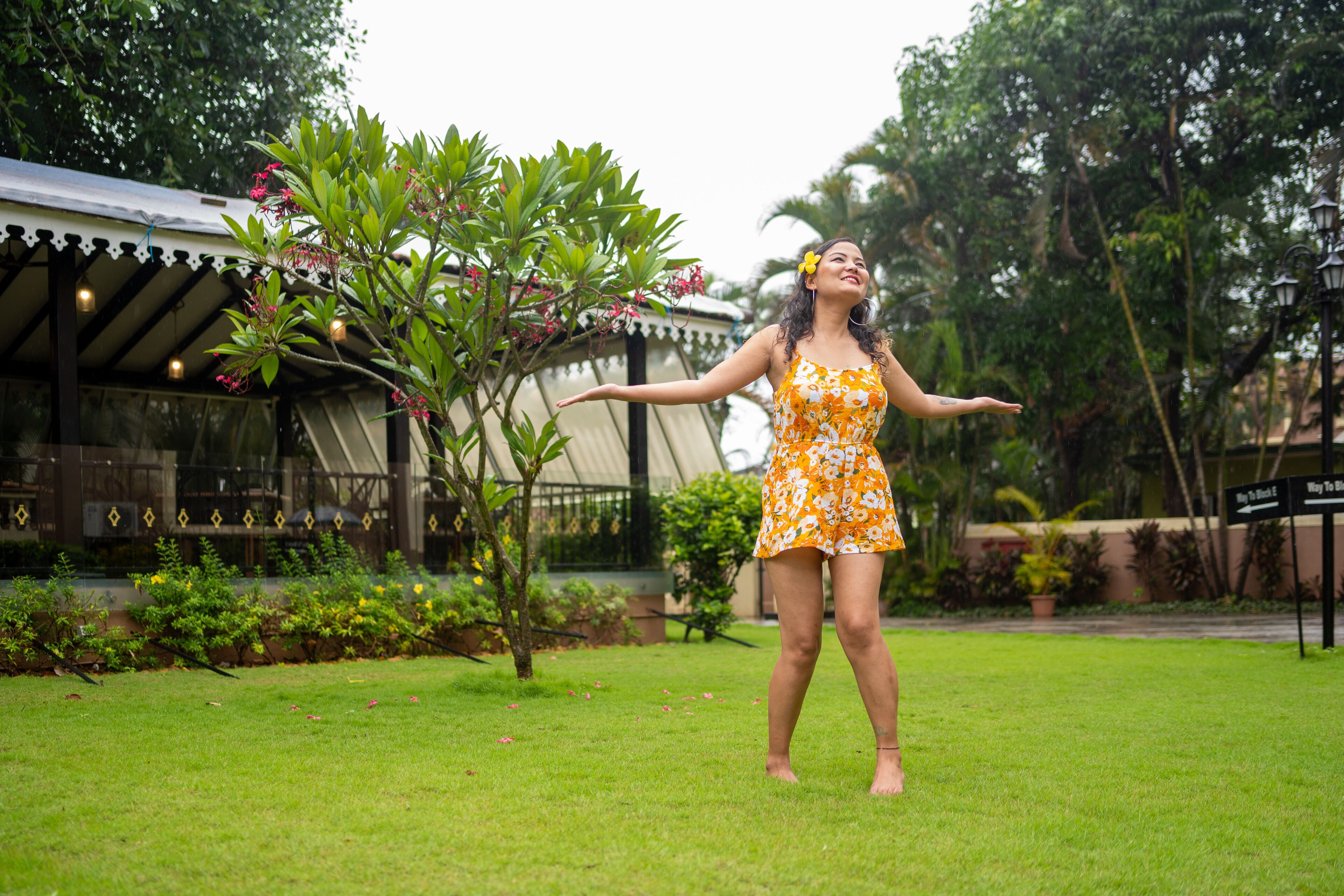 A person in a garden area with a building in the background.