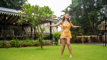 A person in a garden area with a building in the background.