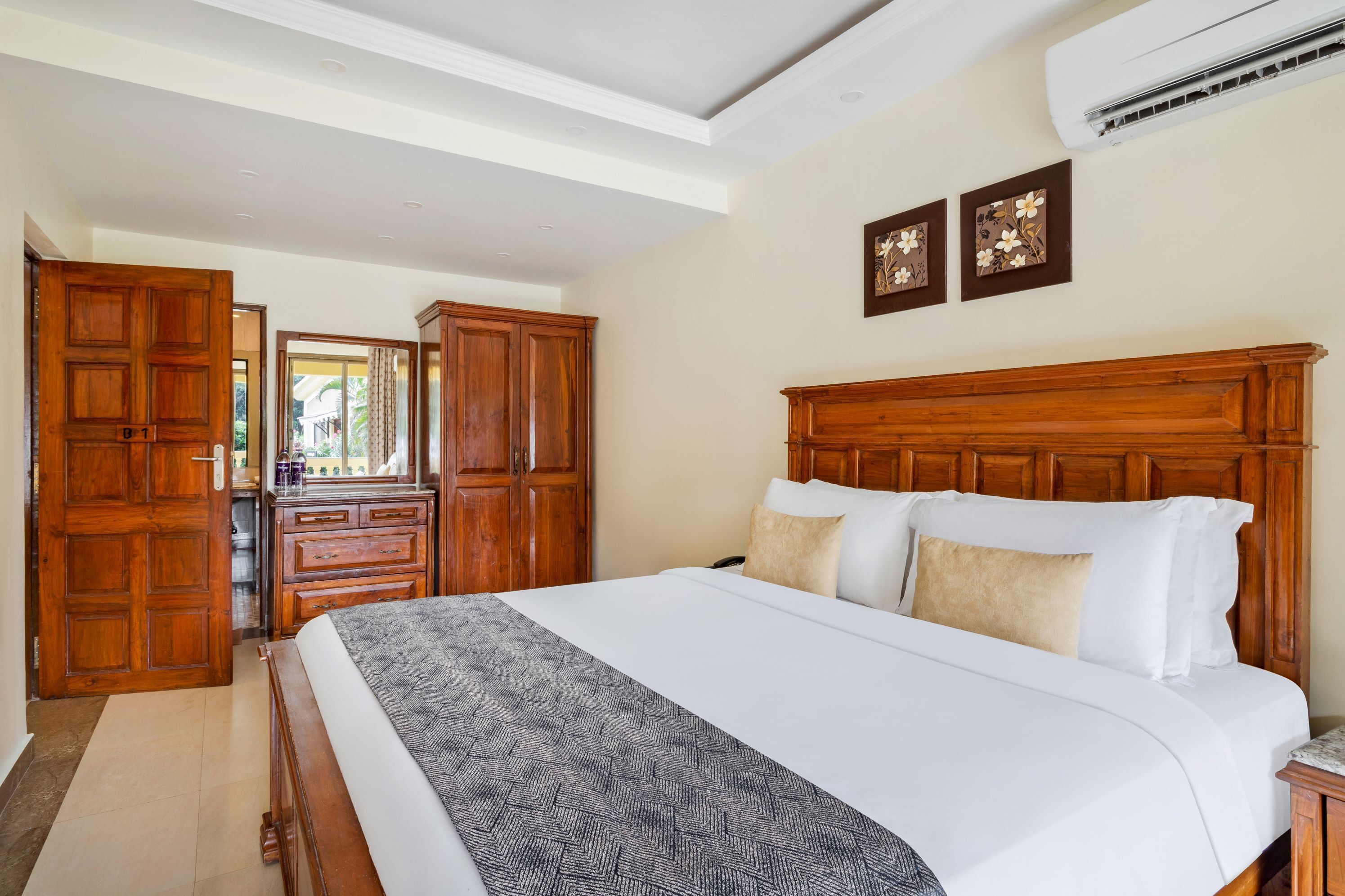 A hotel room with a large bed, wooden headboard, and a view of the outdoors through an open door.