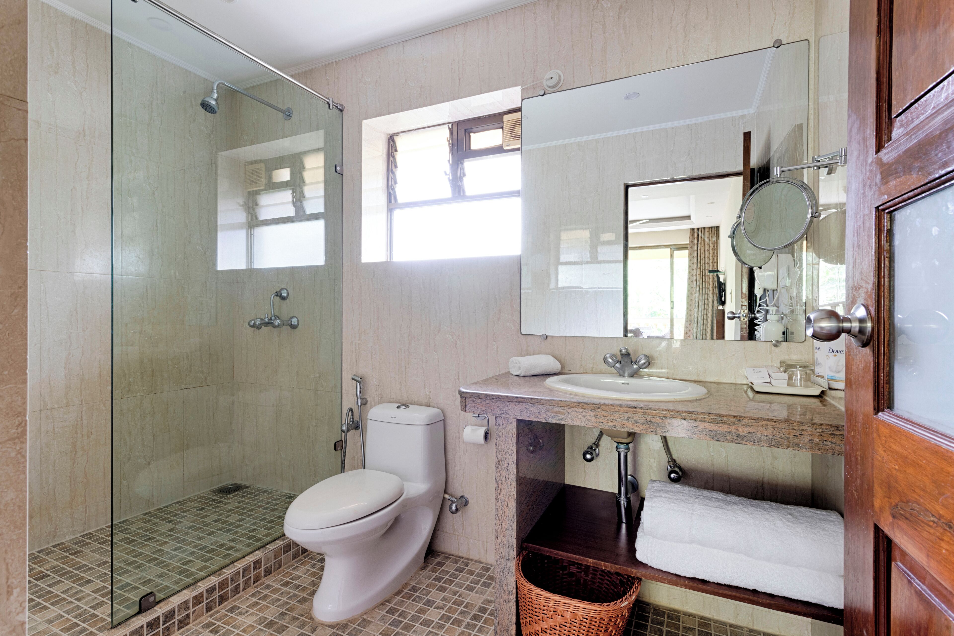 A modern bathroom with a glass-enclosed shower, a toilet, a sink, and a mirror.