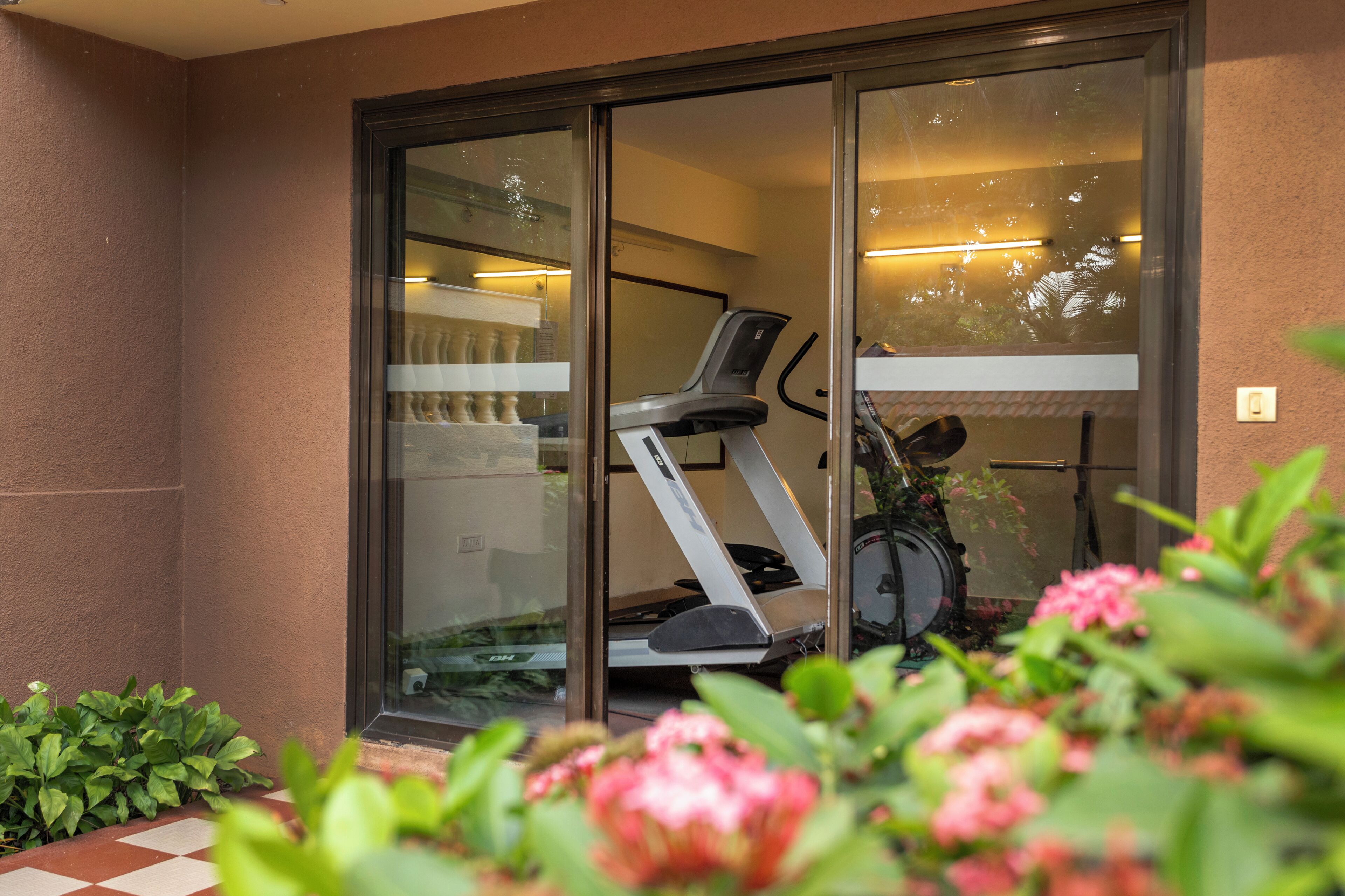 A glass door leading to a room with a treadmill and exercise equipment.