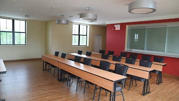 A classroom with long tables and chairs, a whiteboard, and a red accent wall.