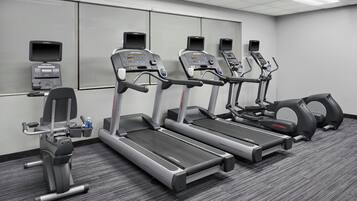Un gimnasio con cintas de correr, una bicicleta estática y una máquina de remo.