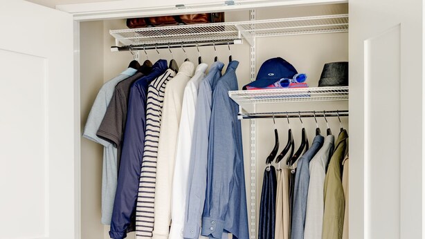 Um closet espaçoso com várias prateleiras para roupas, uma barra para casacos e um sapateiro.