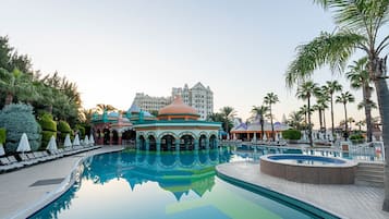 A large swimming pool with a reflection of a building and palm trees.