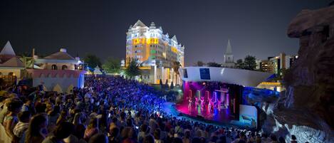 A large outdoor gathering at a venue with a stage and a building in the background.