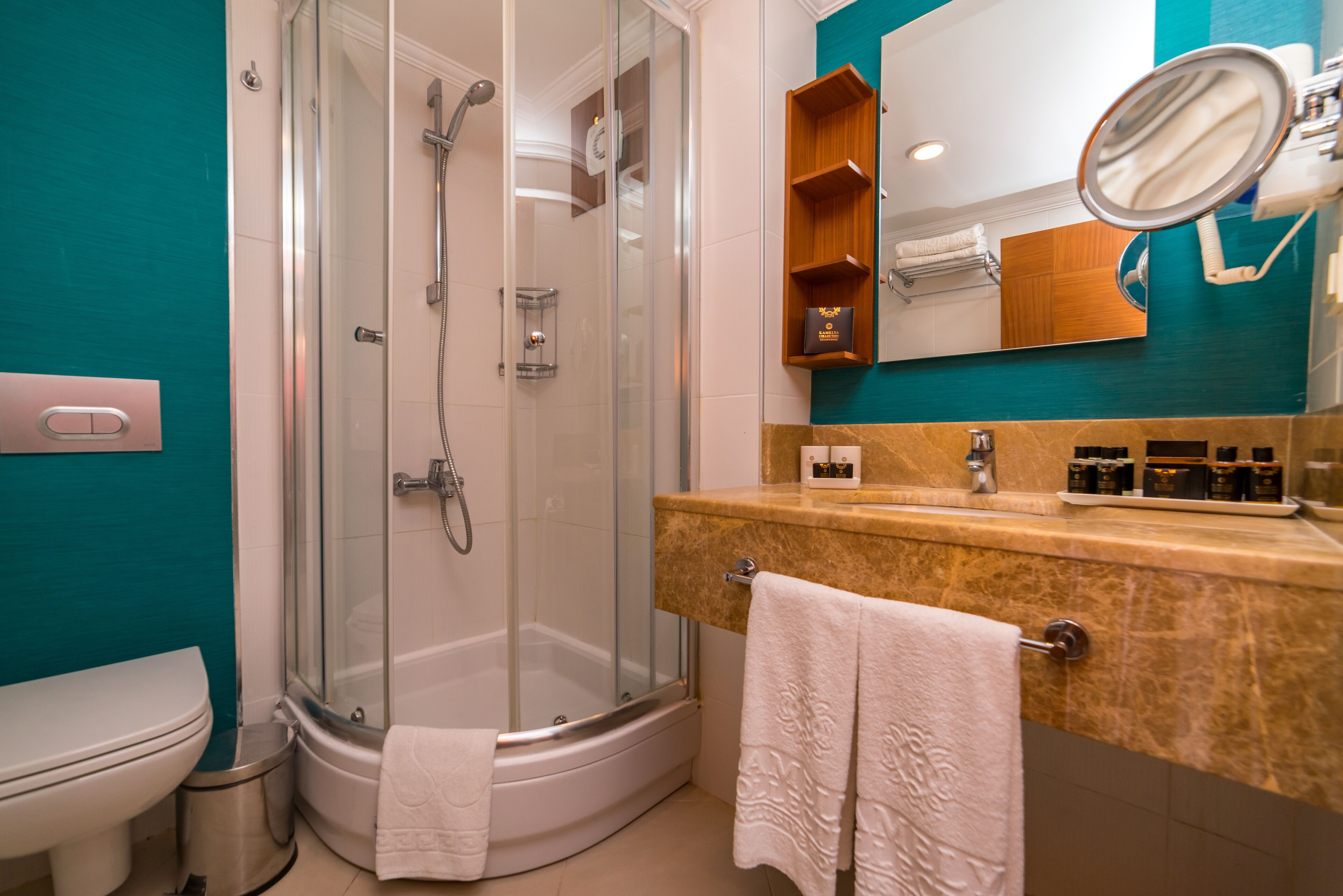 Un baño moderno con ducha envuelta en vidrio, inodoro blanco y tocador con espejo y artículos de aseo.