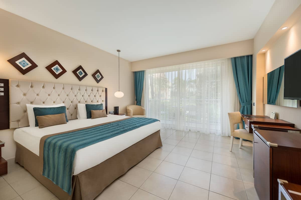 Una habitación de hotel con una cama grande, un escritorio, una silla y un televisor.