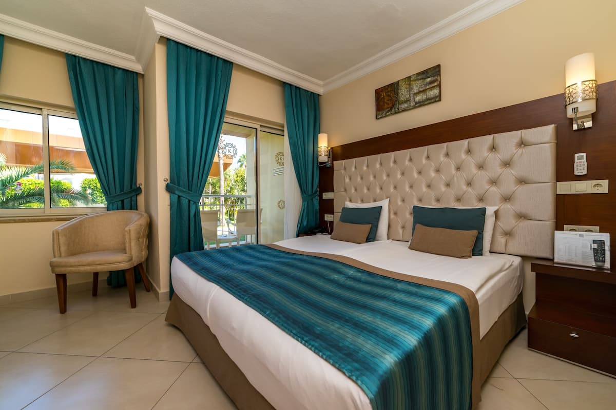 Una habitación de hotel con una cama grande, una silla, una mesita de noche y una ventana con cortinas.