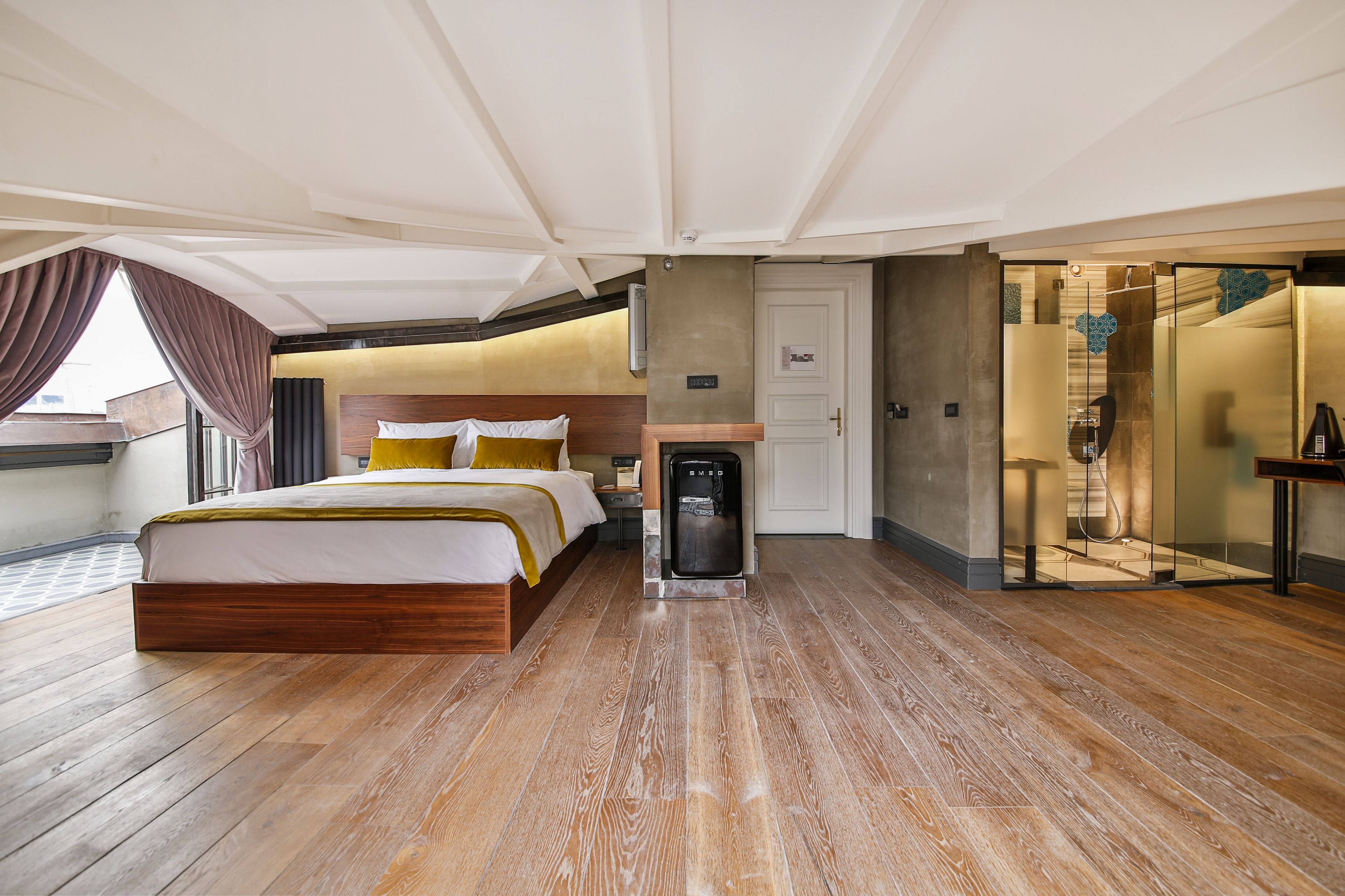 A spacious bedroom with a large bed, a built-in heater, and a glass shower enclosure.