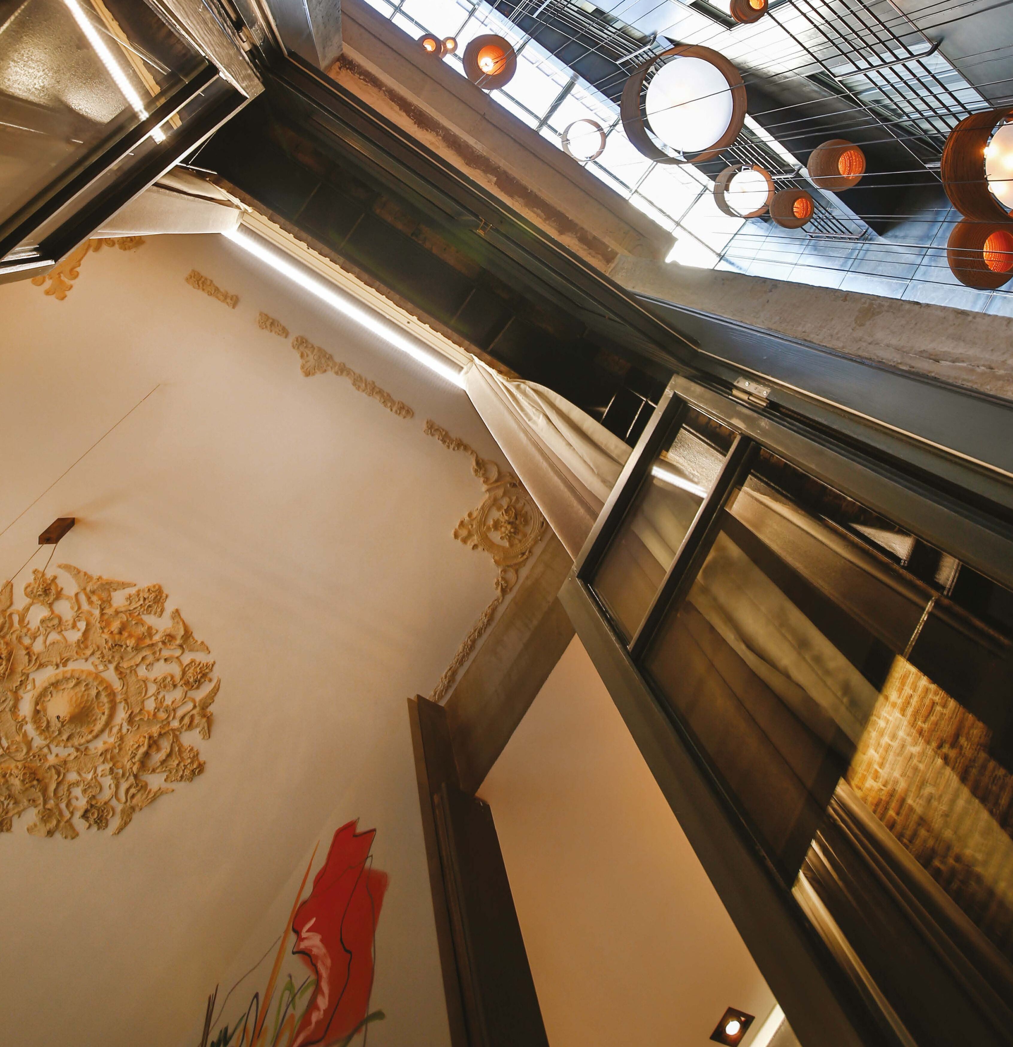 A high-ceilinged interior with a skylight, decorative ceiling patterns, and a modern light fixture.