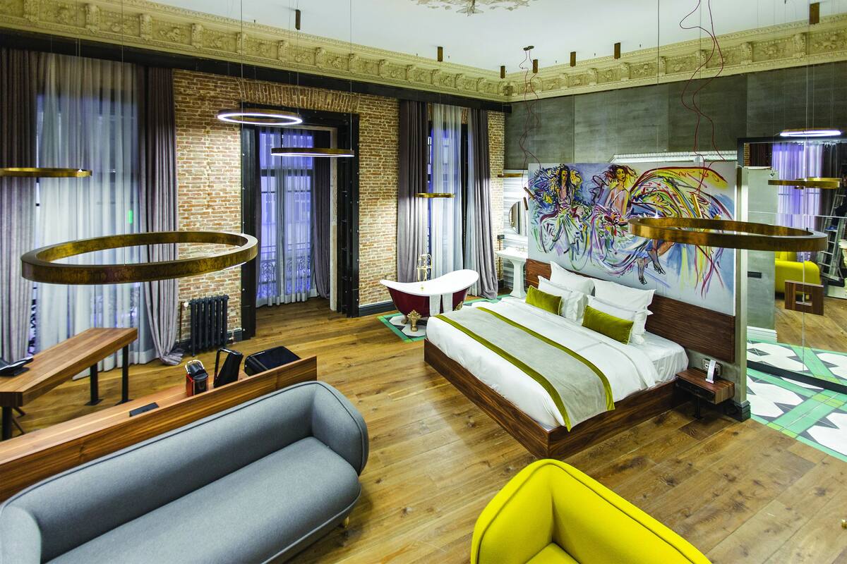 Una habitación de hotel moderna con una cama grande, un sofá, un escritorio y una mesa de comedor.