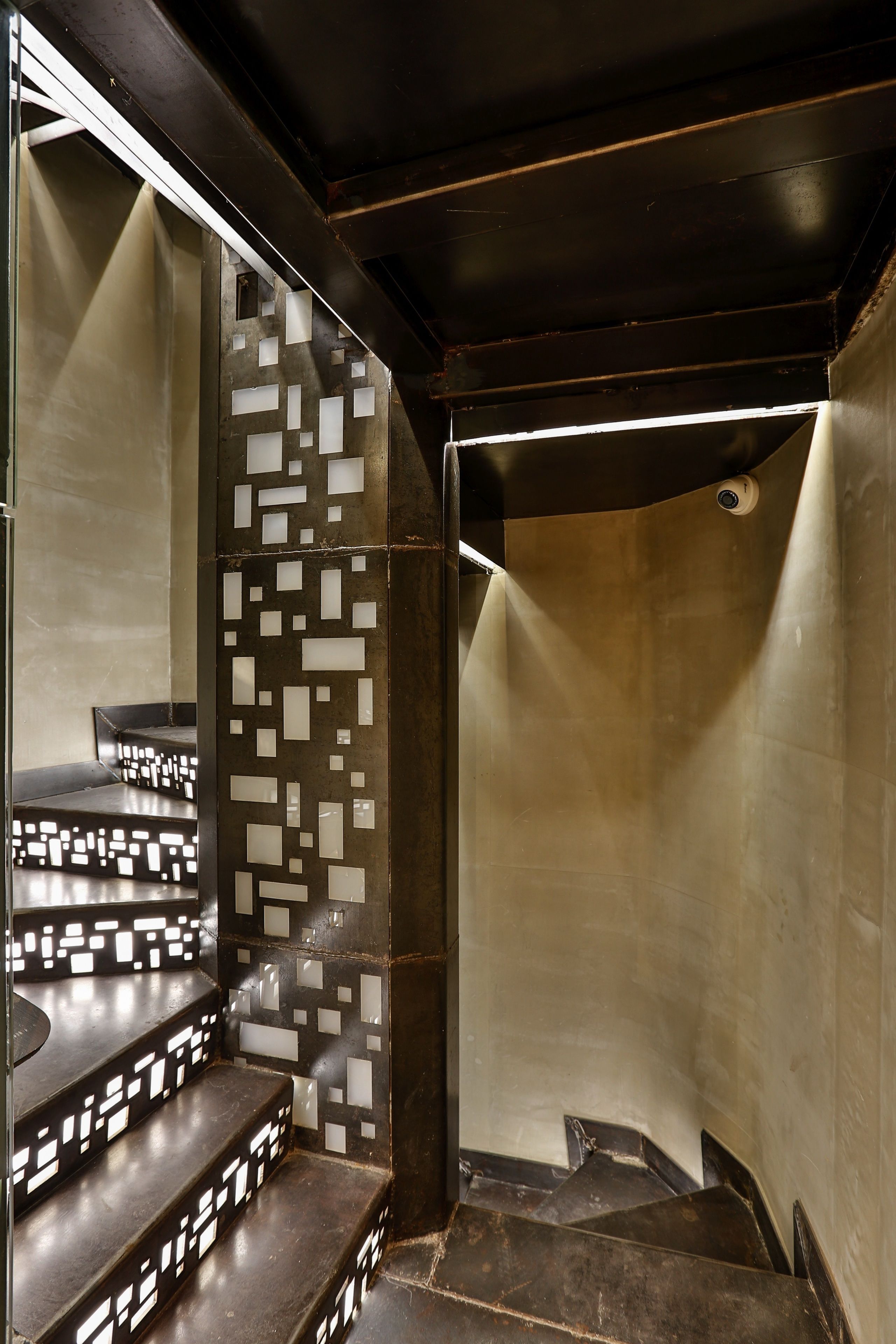 A staircase with a geometric patterned wall and a dark ceiling.
