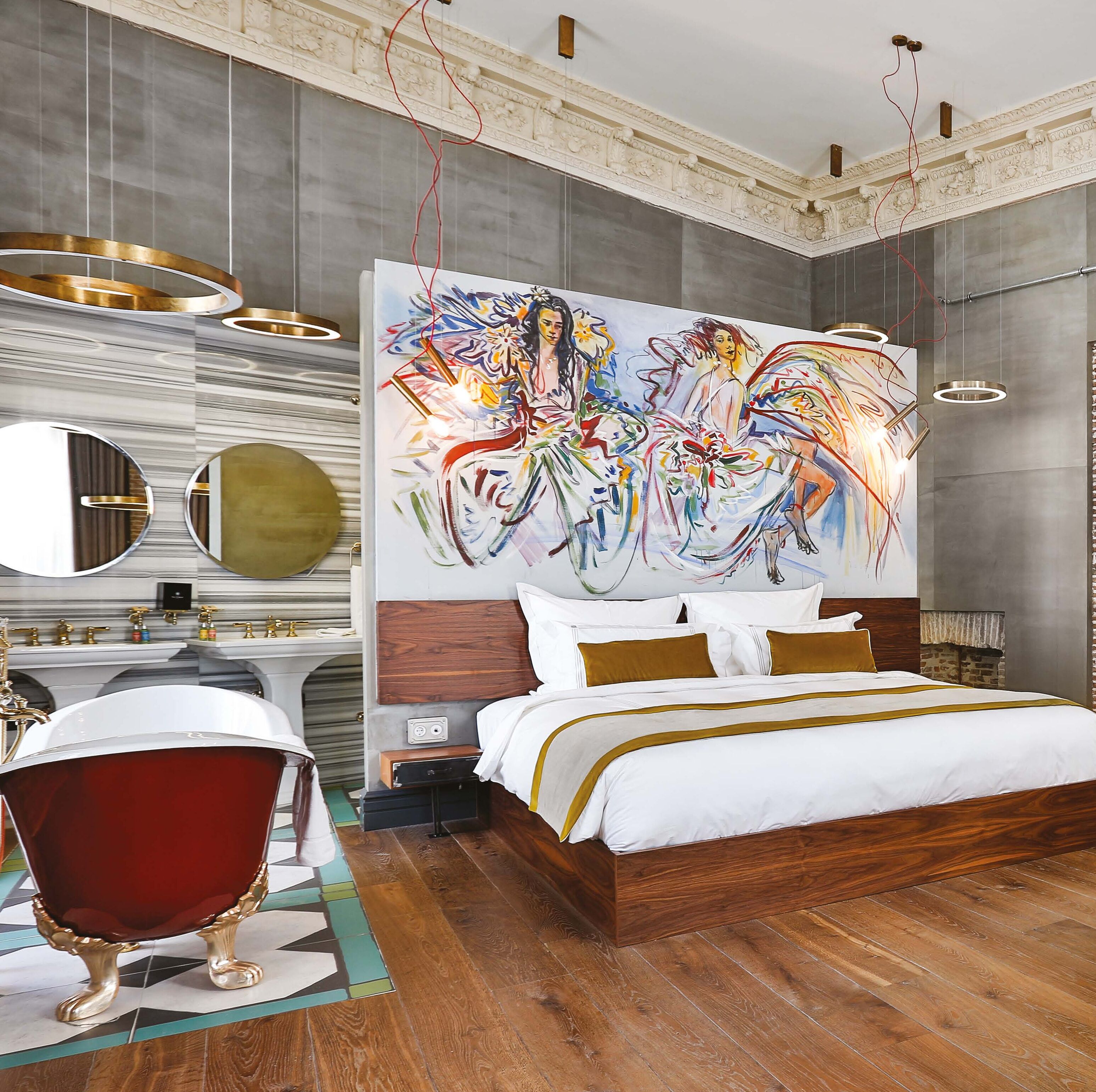 A modern bedroom with a large abstract painting, a classic vanity, and a unique red armchair.