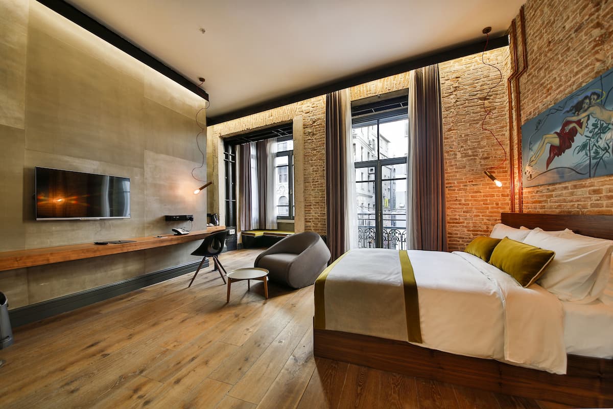 Una habitación de hotel moderna con una cama grande, un escritorio y un televisor montado en la pared.