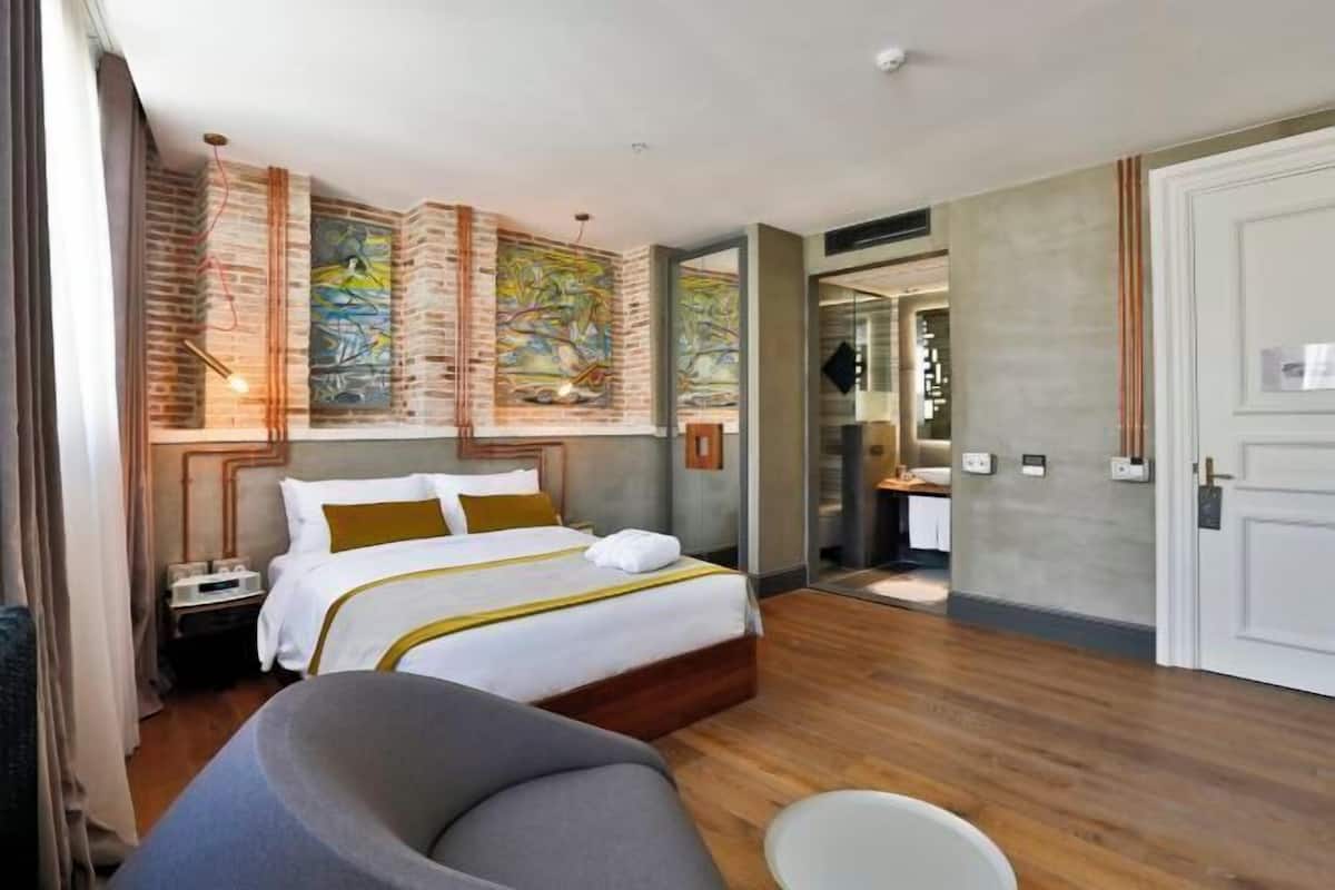 Una habitación de hotel con una cama, una silla, un escritorio y un baño.