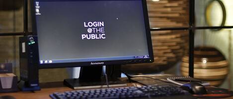 Monitor de computadora Lenovo sobre un escritorio con teclado y ratón, mostrando “LOGIN @ THE PUBLIC” en la pantalla.