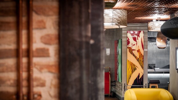 A modern interior with exposed brick walls, a yellow sofa, and abstract wall art. - Hotel The Public (Istanbul)