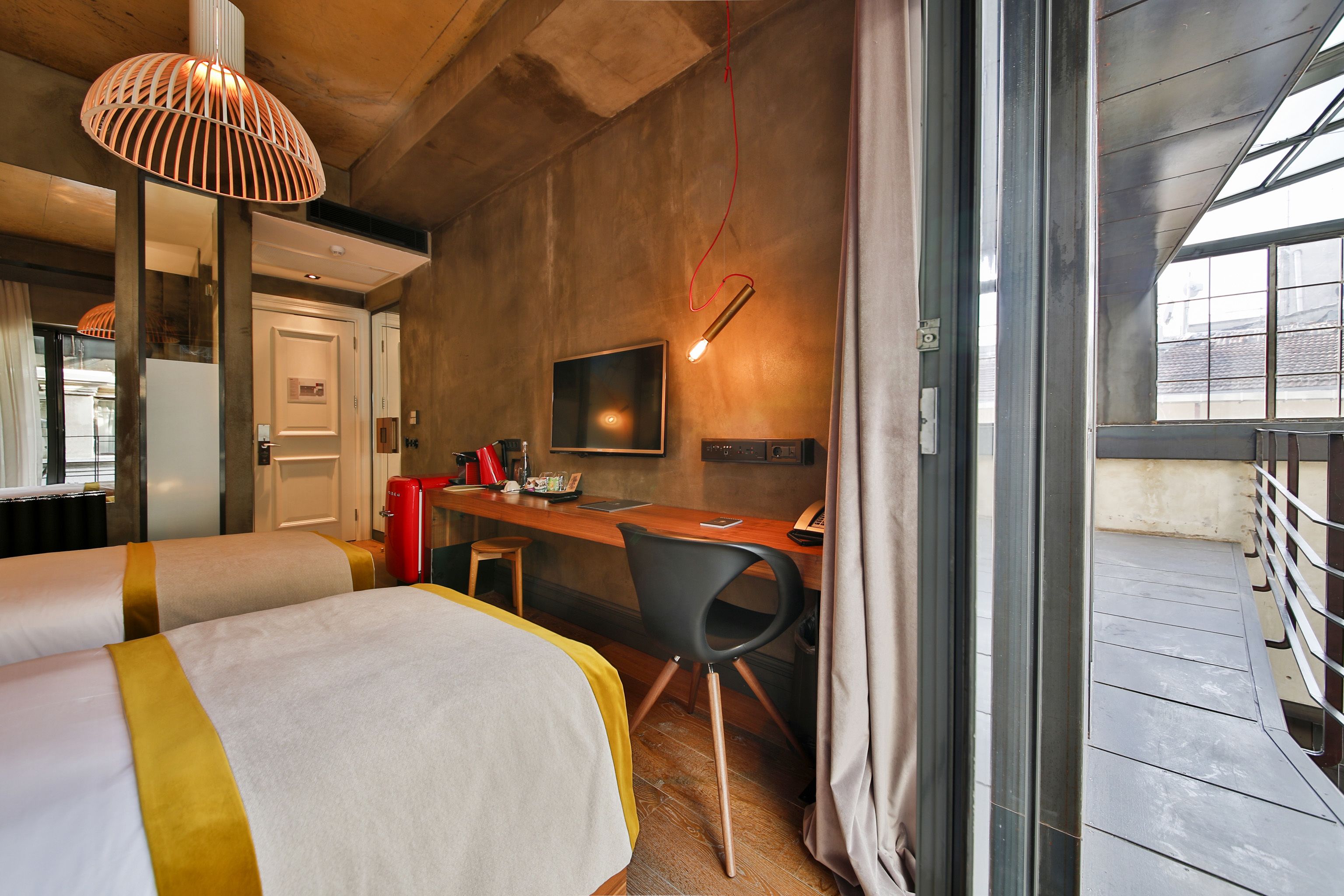 Une chambre d’hôtel avec deux lits, un bureau, une chaise, une télévision et une fenêtre.