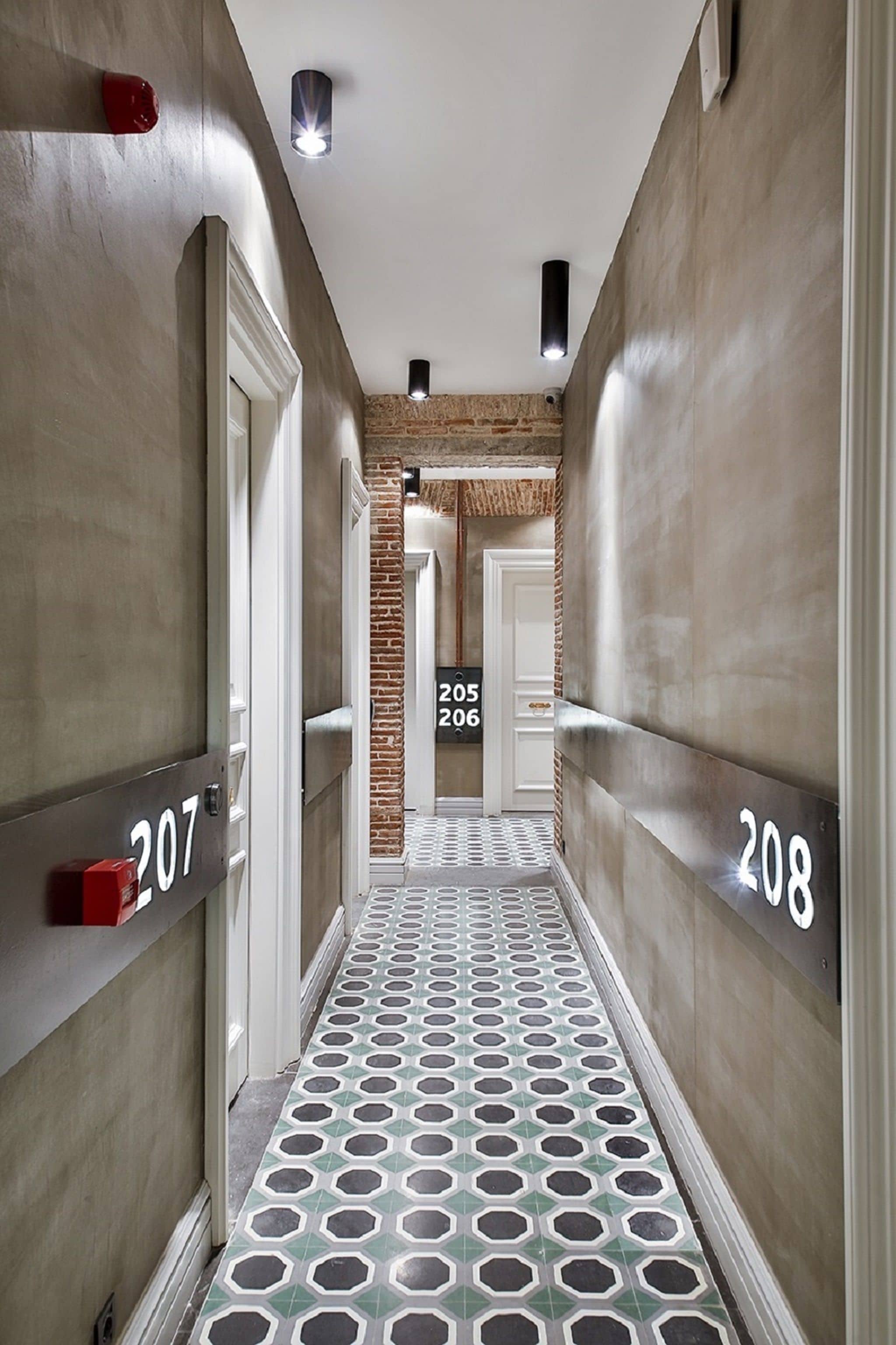 A hallway with numbers 207 and 208 on the walls, a patterned floor, and a brick wall in the background.