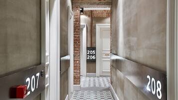 A hallway with numbers 207 and 208 on the walls, a patterned floor, and a brick wall in the background.