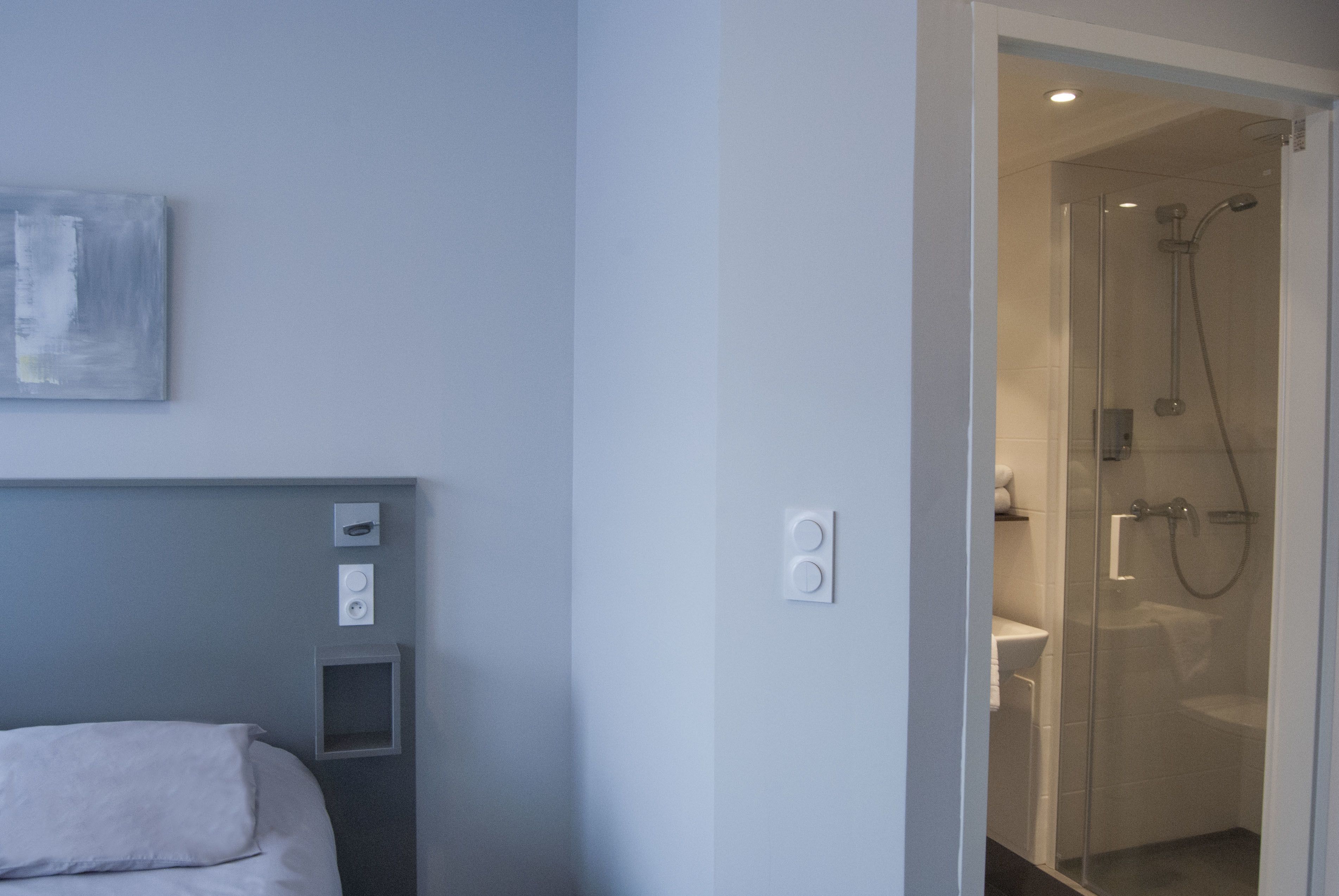 A modern bathroom with a glass shower enclosure, a visible toilet, and a wall-mounted light fixture.