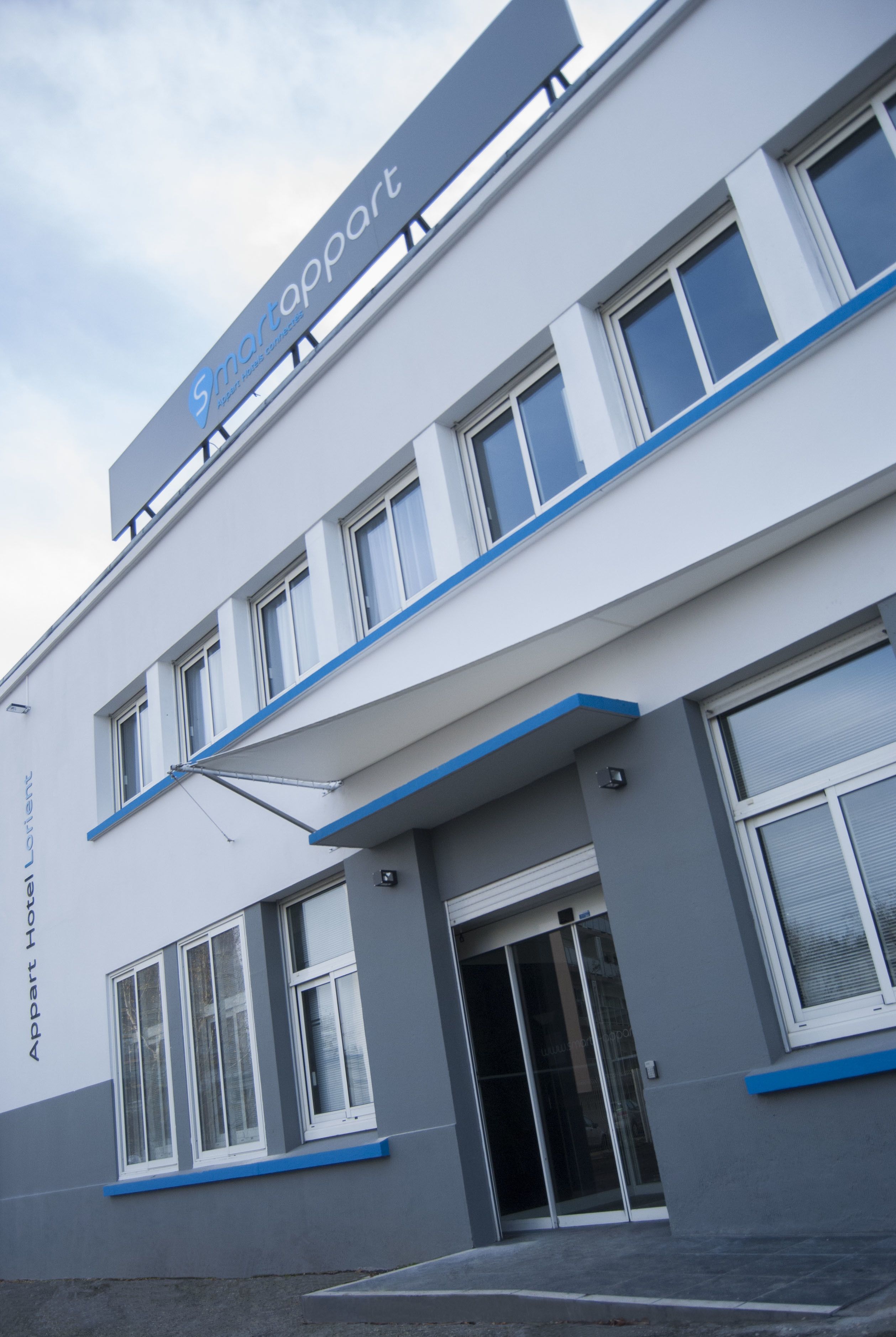 A modern building with a sign reading "Smartappart" and a glass entrance.