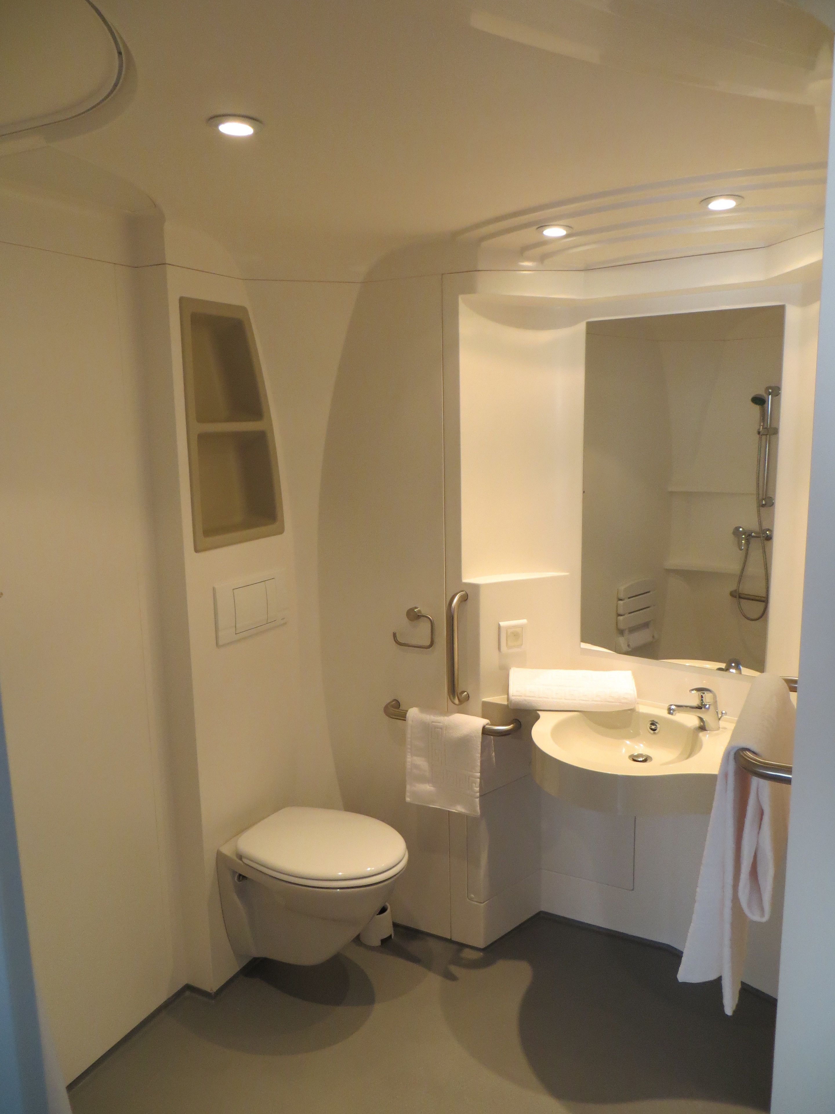 A compact bathroom with a toilet, sink, and shower.