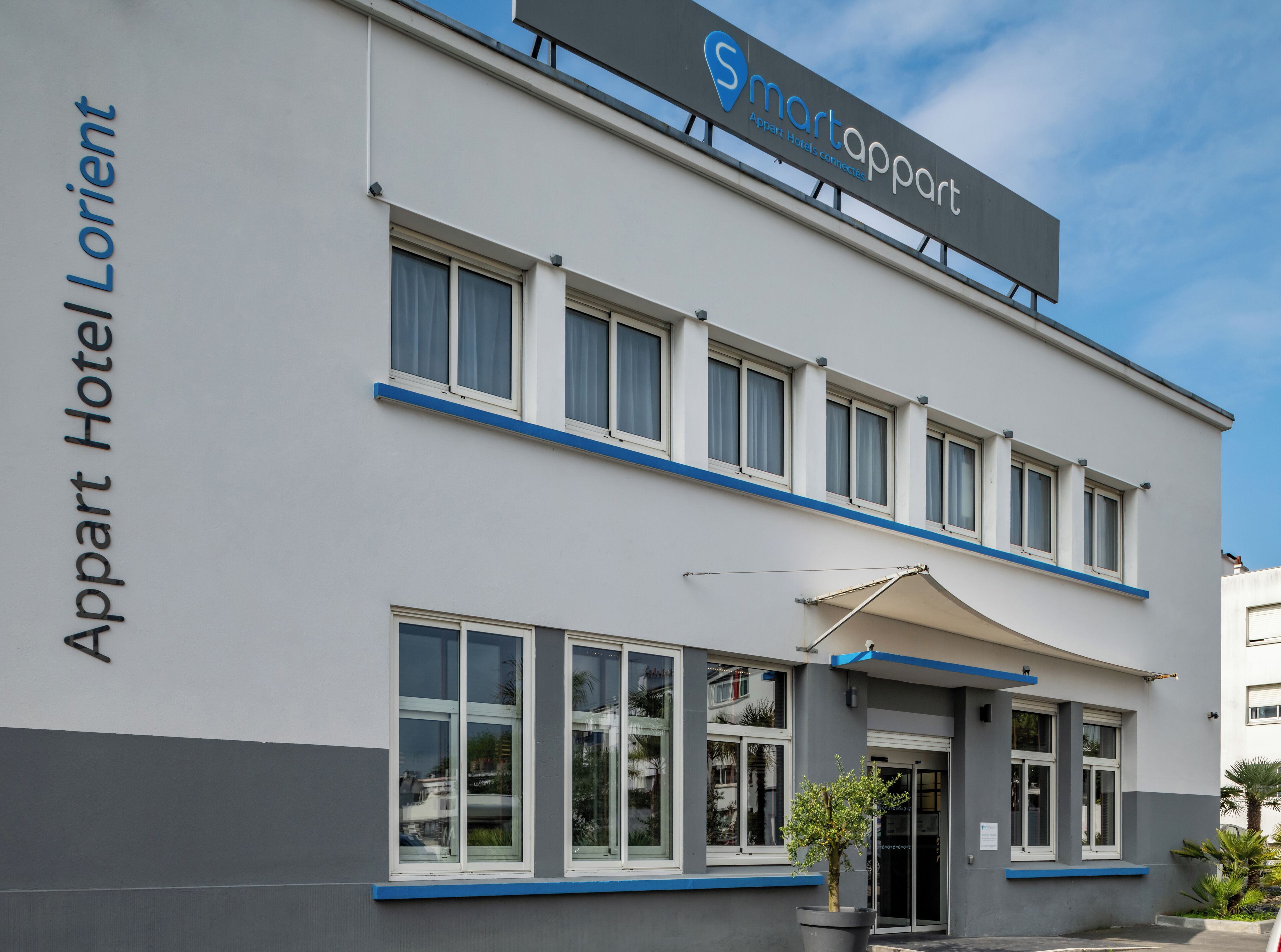 Ein zweistöckiges Gebäude mit einem Schild, auf dem „Smartappart“ und „Appart Hotel Lorient“ steht, das es als Smartappart Hotel in Lorient kennzeichnet.