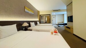 Une chambre d’hôtel avec deux lits, une télévision, un bureau et une salle de bain visible à travers une porte ouverte.