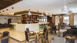 Un espace bar moderne comprenant un comptoir, des tabourets de bar et un coin salon avec des canapés et des fauteuils.