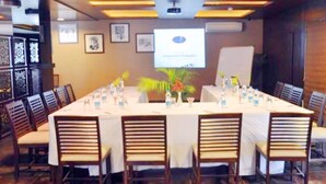 A conference room with a long table, chairs, a projector screen, and a presentation on the wall. - Ginger Vadodara,Alkapuri (Vadodara)