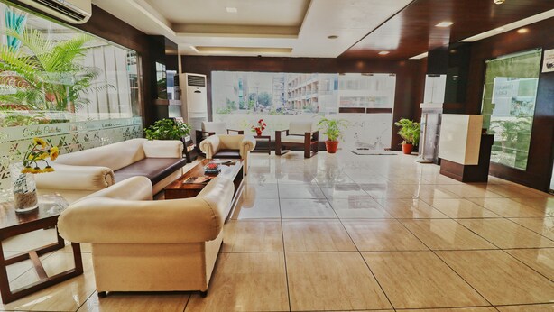 A hotel lobby with a seating area, a reception desk, and a view of the cityscape through large windows. - Ginger Vadodara,Alkapuri (Vadodara)