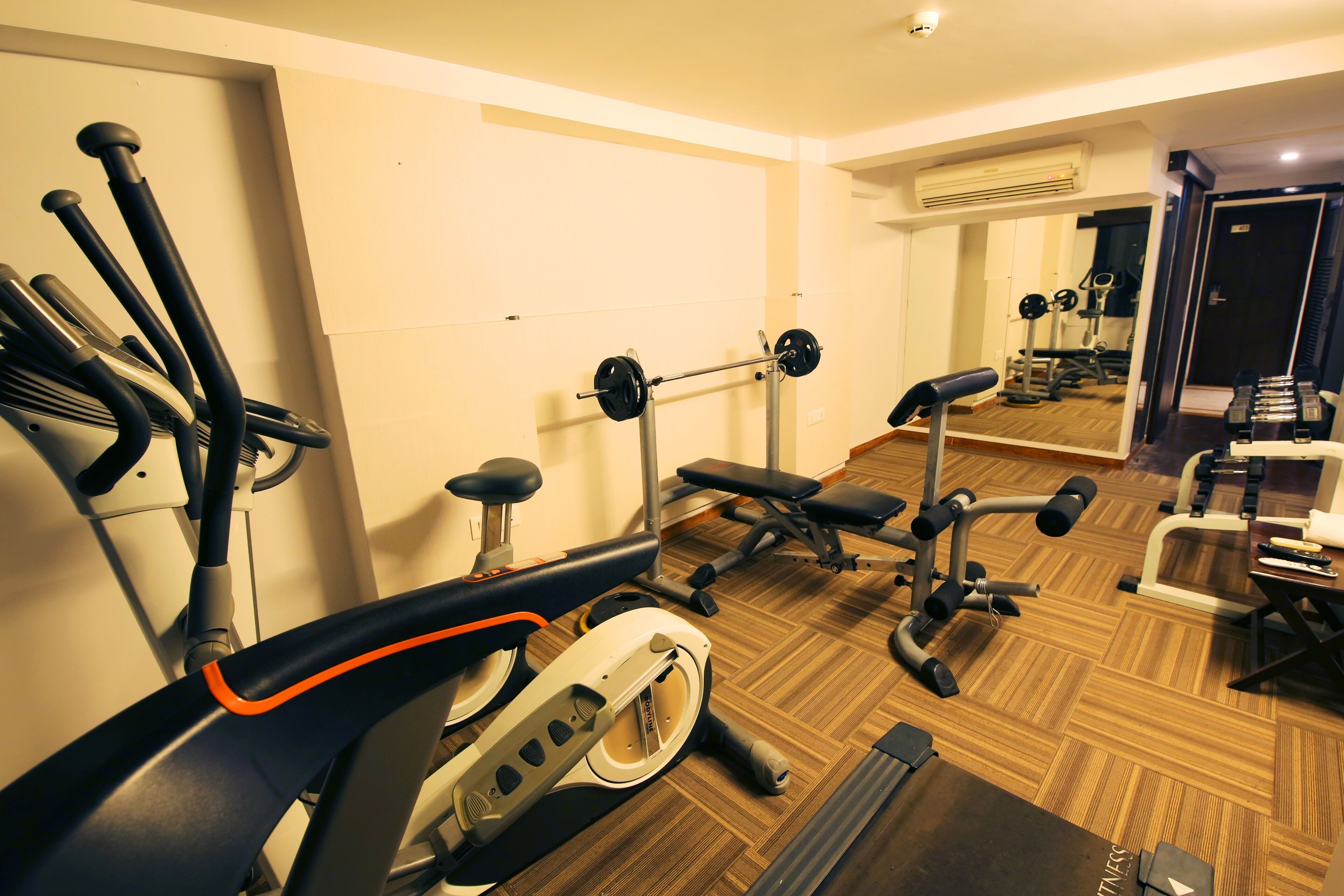 A gym with cardio equipment, weight machines, and a mirrored wall.