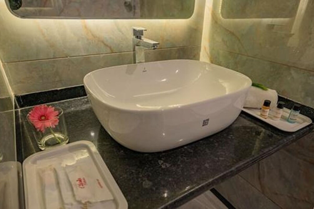 Un baño con un lavabo blanco grande, un espejo y una encimera de mármol.