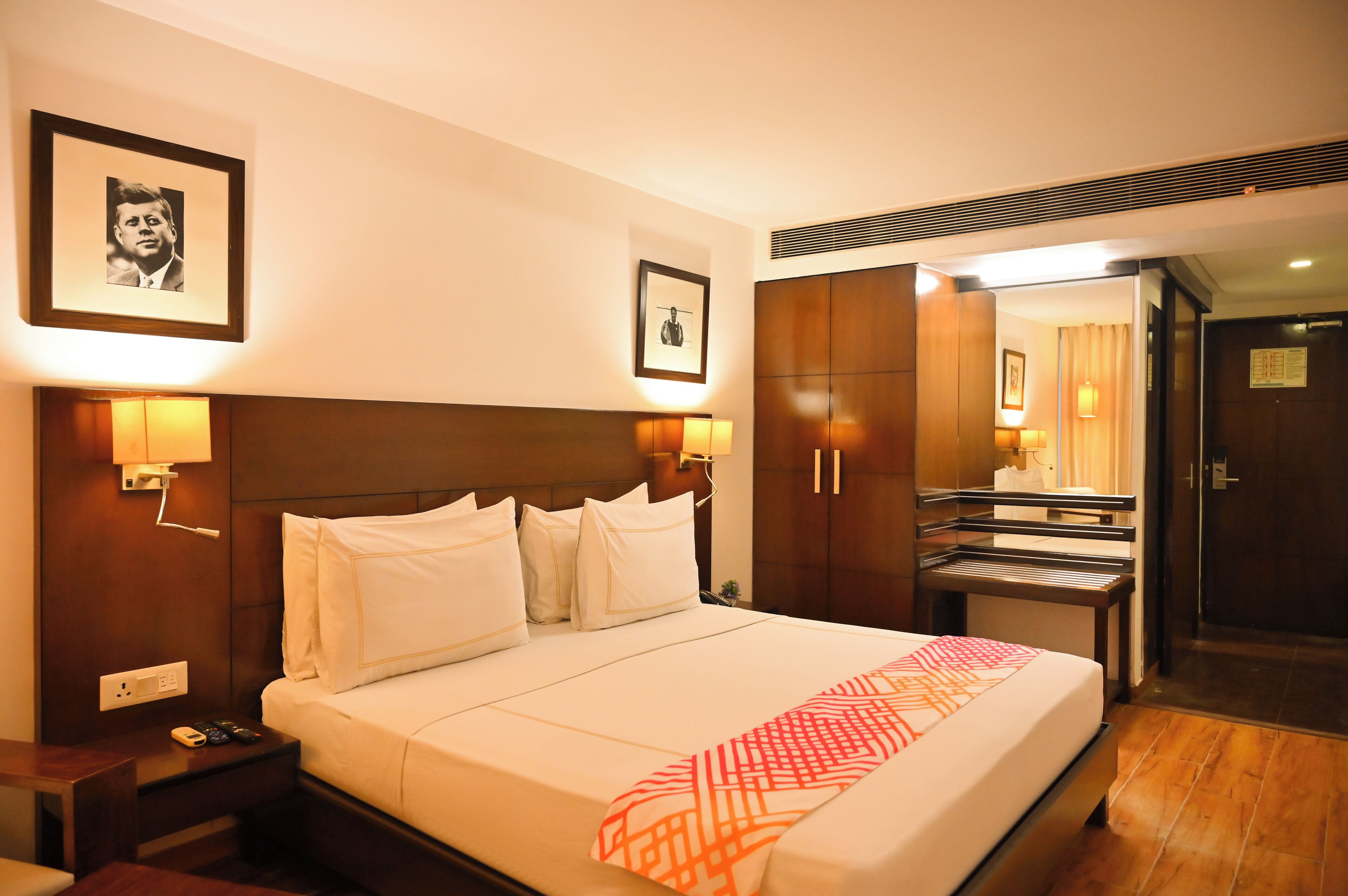 A hotel room with a large bed, bedside lamps, a wardrobe, and a mirror.