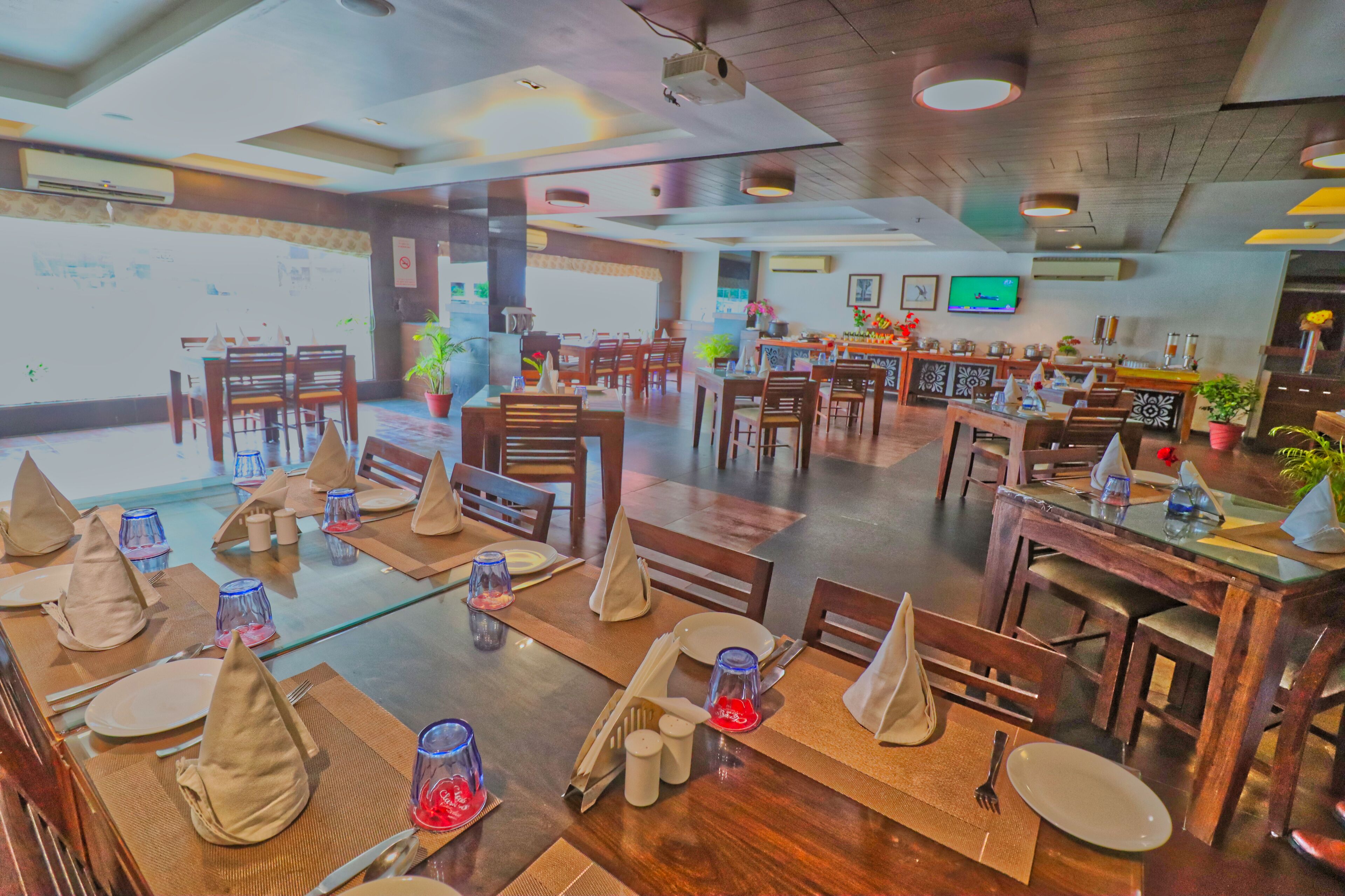 A restaurant with multiple dining tables set with tablecloths, napkins, and cutlery.