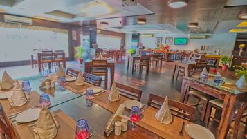 A restaurant with multiple dining tables set with tablecloths, napkins, and cutlery.